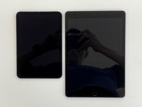 反射防止コーティングありのiPad mini（左）と、なしの無印iPad（右）。iPad miniにはほとんど映っていないが、無印iPadは光を反射し、撮影している筆者の姿も映っている。