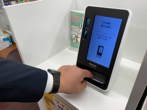 マイナンバーカードを顔認証付きカードリーダーにかざしている様子