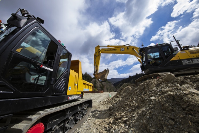 宮崎県椎葉村の工事現場で稼働する2台の建設機械。オペレーターは乗っていな い。右側にあるバックホーは遠隔地で操作しており、土砂の積み込みが終わると左側のクローラーダンプが自律搬送する(写真:イクマ サトシ)