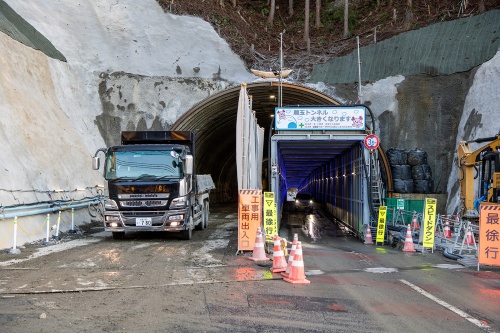 トンネル拡幅部上部の掘削が進む蔵玉トンネルの北側坑口。プロテクターで覆われた写真右側の道路を一般車両が通行する。（写真：大村 拓也）