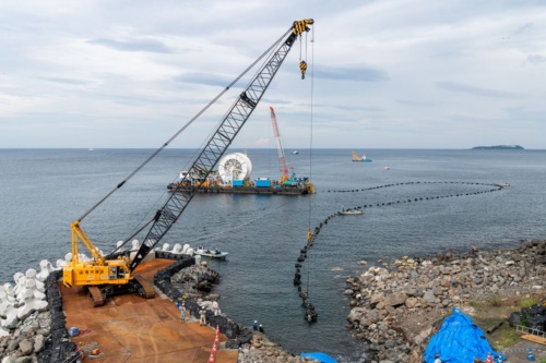 初島側から設置してきた海底送水管を、クローラークレーンで吊り上げながら、本土へ引き込む(写真:大村 拓也)