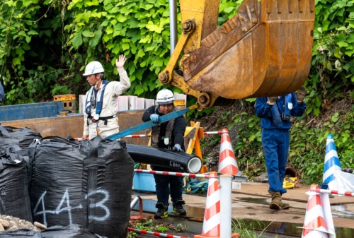 陸上でバックホーを用いて送水管を運ぶ様子(写真:大村 拓也)