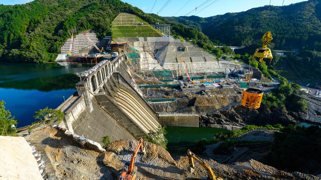 現場上空をバケットが自律運転で往来　大林組、ダム堤体打設の自動化へ実験