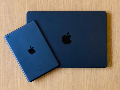 初代「iPad mini」の「ブラック＆スレート」とM2 MacBook Airのミッドナイトを並べたところ。どちらもアルミ素材で濃い黒。やや青みがかかっている点も似ている