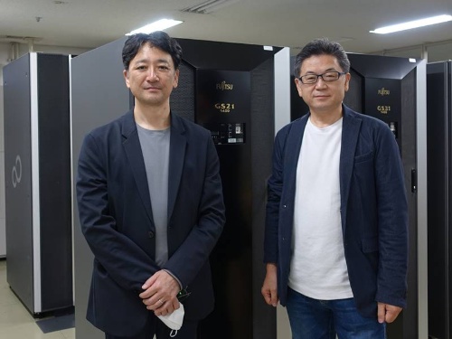 ベイシアグループソリューションズの平田稔ソリューション統括本部オープン化推進部部長(左)と執行役員を務める重田憲司ソリューション統括本部本部長。後ろに映るのは以前利用していたメインフレームのきょう体