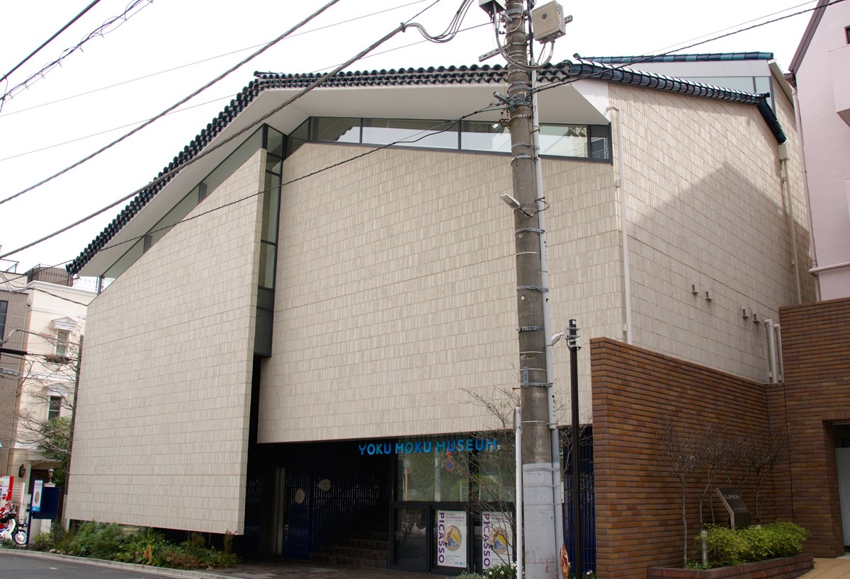 「ヨックモックミュージアム」（東京都港区南青山6-15−1）の設計は栗田祥弘氏。2階建ての小さなボリュームが組み合わさった家型の外観となっており、「市中の山居」のように中庭を通じて光、風、植物を感じられる空間という。同ミュージアムのウェブサイトによると、屋根はピカソがセラミック制作をしていたコートダジュールの瓦ディテールをオマージュし、床や壁は陶芸窯で使われている耐熱れんがをイメージしているという（写真：渡辺 圭彦）