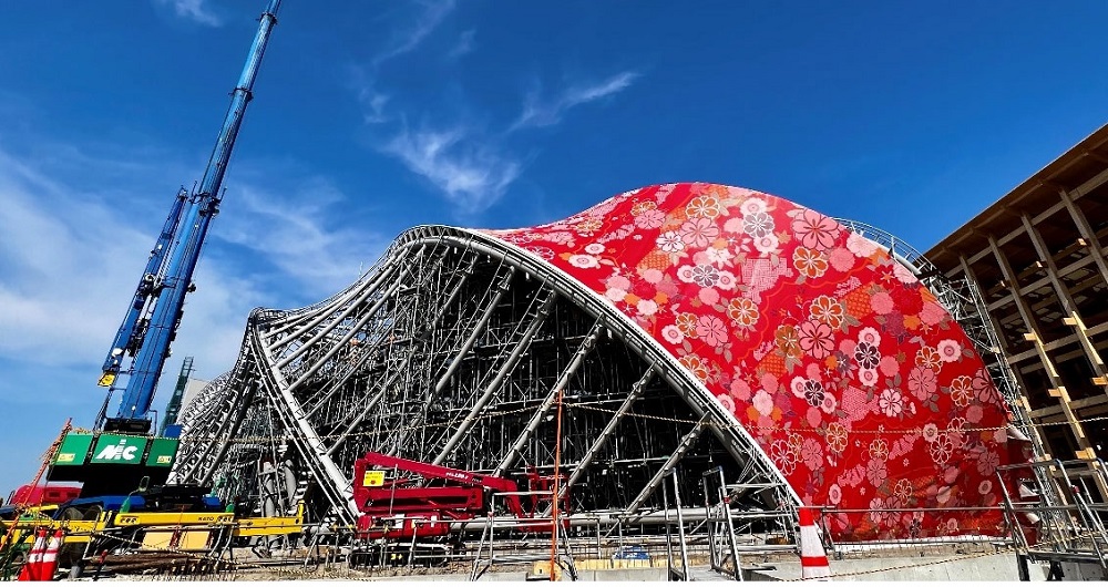 大阪・夢洲（ゆめしま）で万博パビリオン「飯田グループ×大阪公立大学共同出展館」の躯体（くたい）に、西陣織の膜を取り付ける工事が始まった（写真：飯田グループホールディングス）