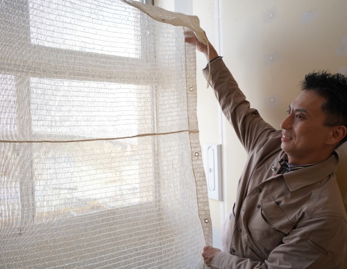 和紙のシェードを広げる、東畑建築事務所設計室の平野尉仁部長(写真:日経クロステック)