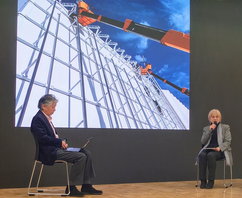 未来の都市パビリオンの建築コンセプトや照明演出について説明する、SD ASSOCIATESの岡崎恭子氏（右）（写真：日経クロステック）