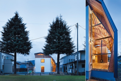 左:南東側から見る。木造在来軸組み工法の“四角い箱”を、ボールト形式の屋根が覆う。多角形断面の屋根架構は、北側外壁の桁上と南側の基礎部の土台で支持し、南側全体を覆うように架けている 右:妻側に設けた開口部。ステンレスと木の特注サッシによるFIX窓だ。屋根の薄さや軽さを際立たせる。外観は、在来工法の部分を左官仕上げとし、ボールト屋根部と見え方を分けた(写真:繁田 諭)