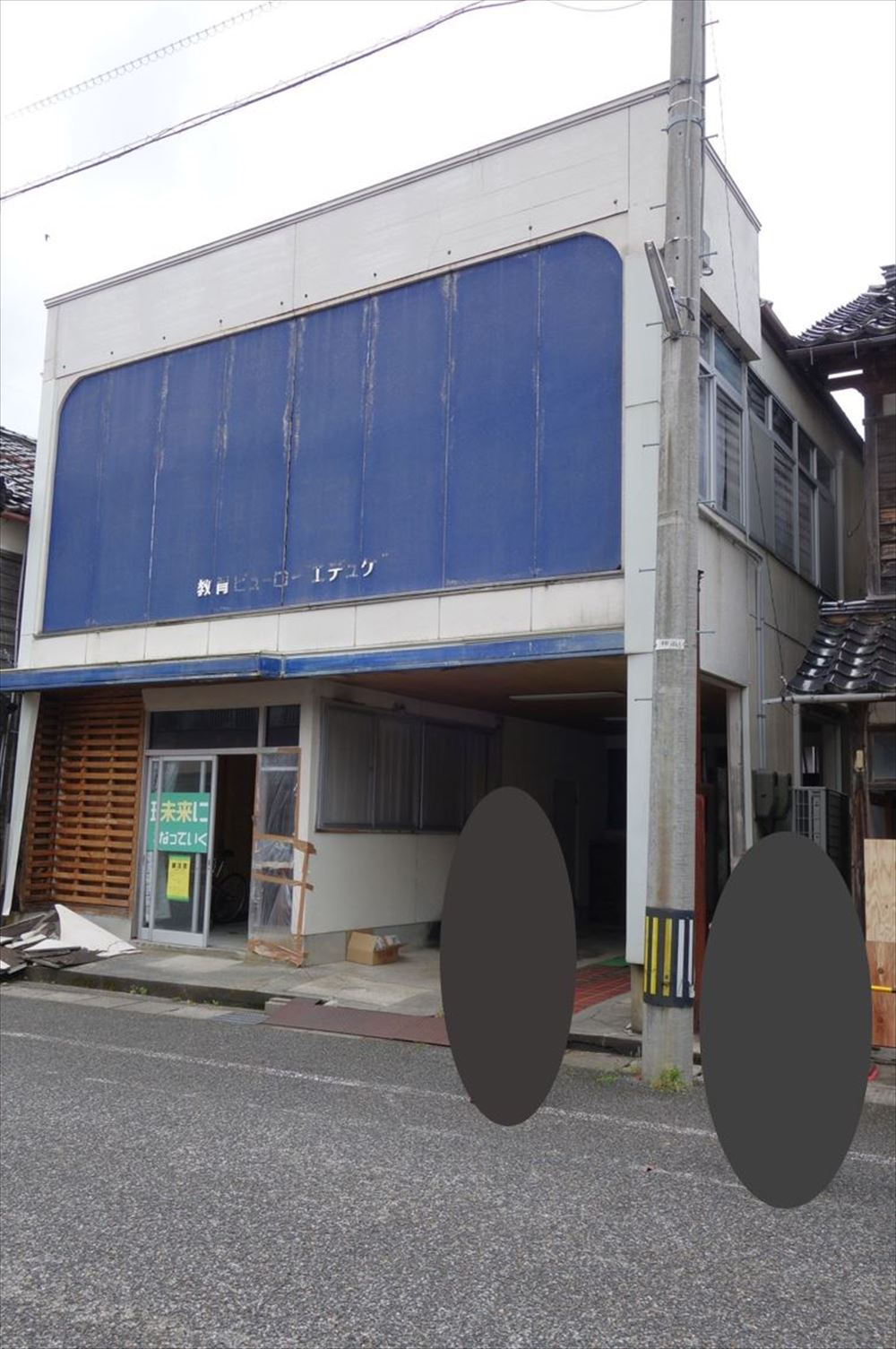 珠洲市正院町に立つ木造2階建て事務所の23年奥能登地震後の状態。入り口とその周りの外装材が損傷した（写真：建物修復支援ネットワーク）