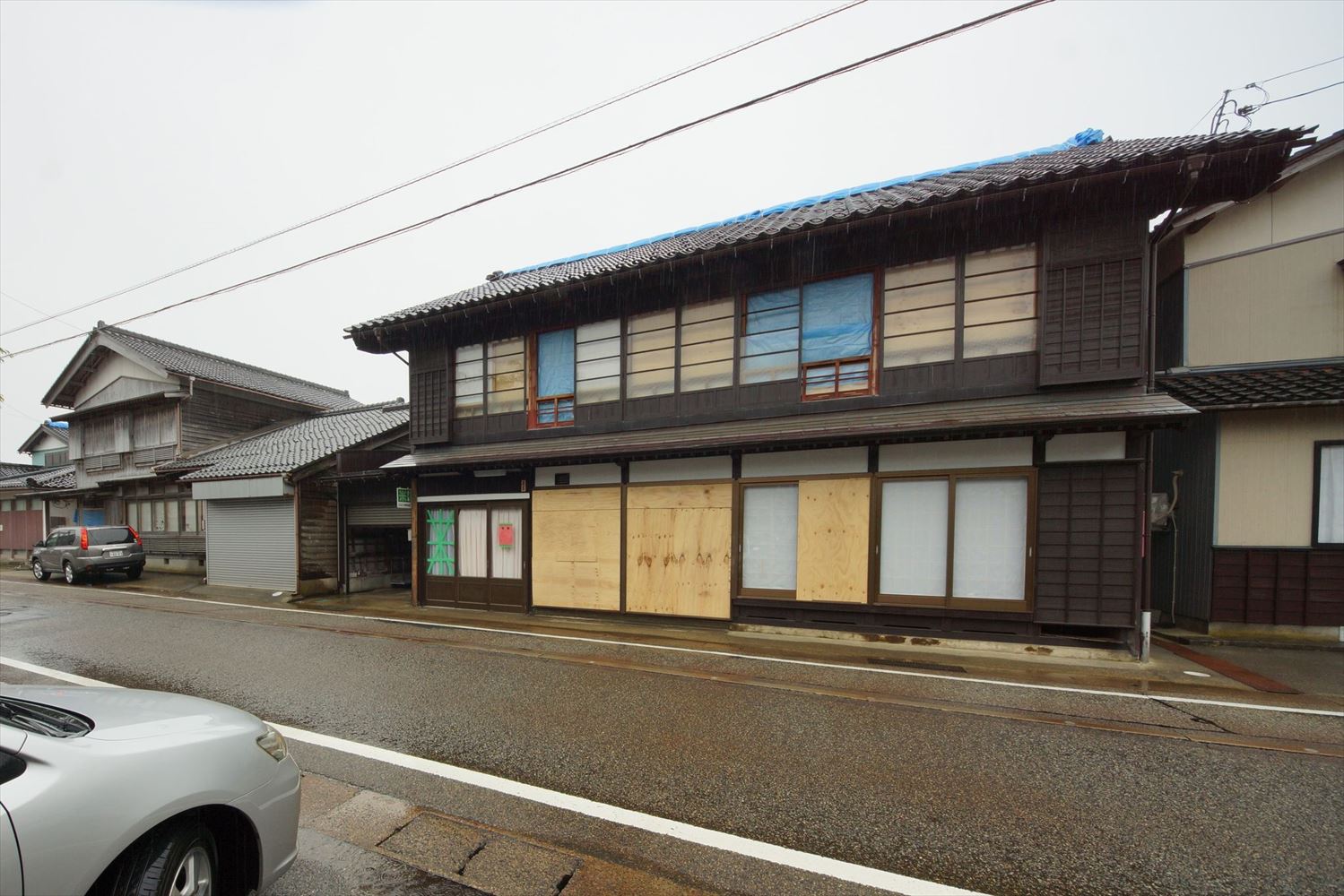 珠洲市正院町に立つ間口の広い住宅の23年奥能登地震後の状態。奥能登地震では大きな変形は生じなかった。道路側建具の一部は破損したので合板を張っている。1993年の能登半島沖地震後に、筋交い（すじかい）と火打ち梁（はり）を追加する耐震補強を実施していた（写真：建物修復支援ネットワーク）