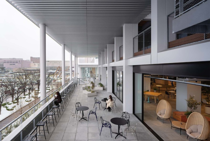 JR金沢駅を望む4階テラス。ラウンジ側は全面開放が可能な引き戸になっている。屋外の空気を感じながら思い思いにくつろげる。テラスの両端に階段があり、駐車場から直接アクセスできる(写真:浅田 美浩)