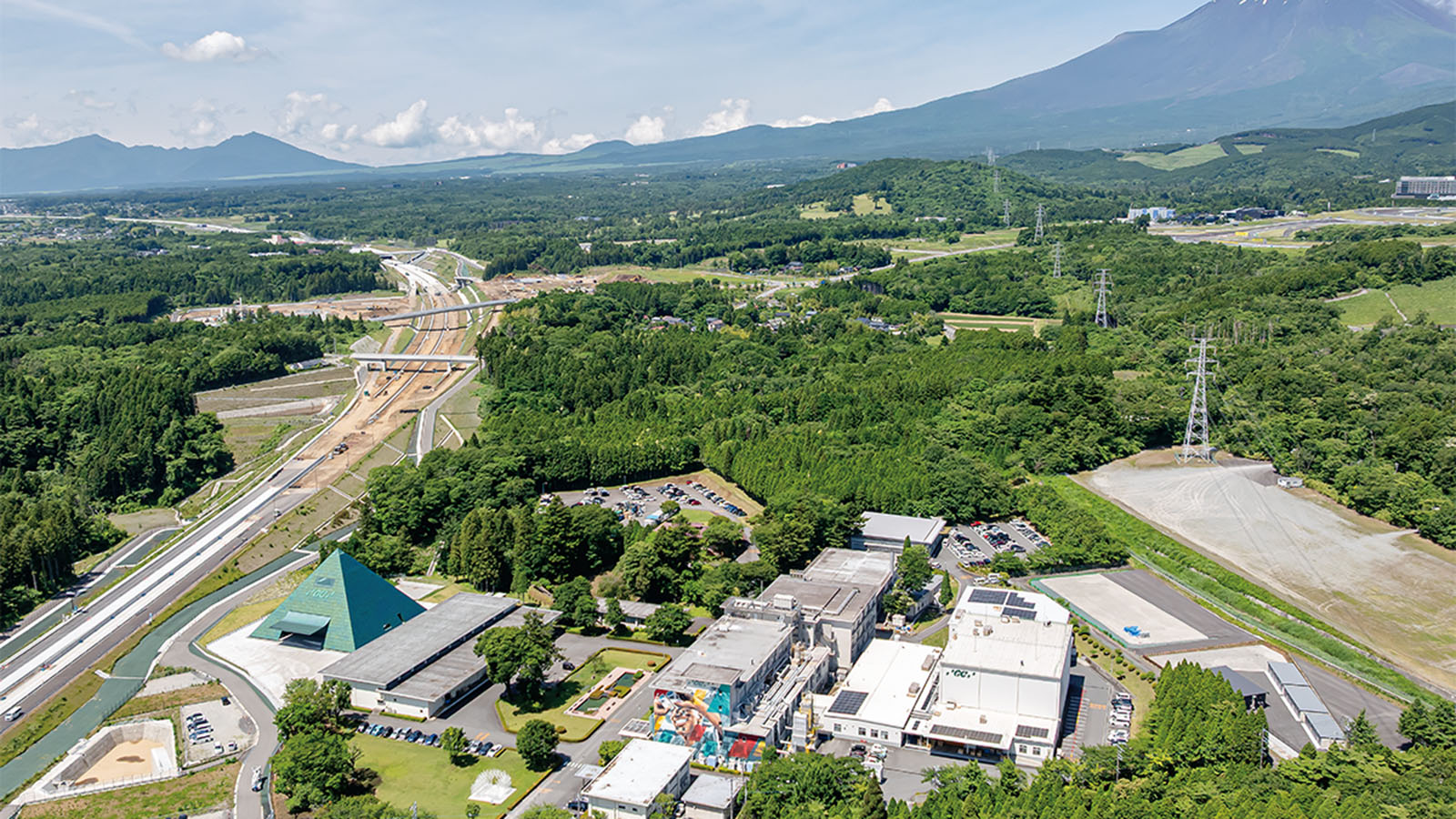 富士山麓で緑色に輝くピラミッド、新東名の脇に立つ坂茂氏設計の工場