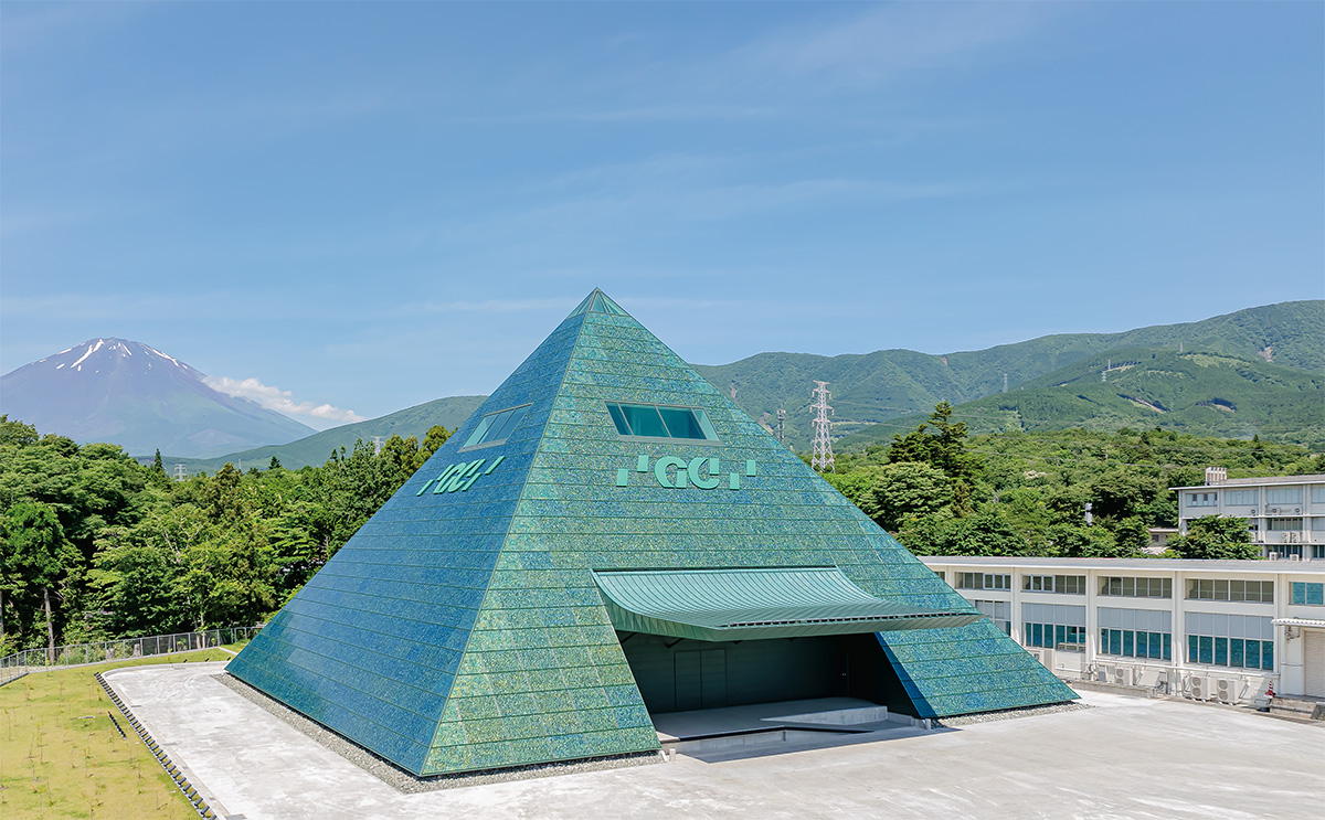 富士山麓で緑色に輝くピラミッド、新東名の脇に立つ坂茂氏設計の工場