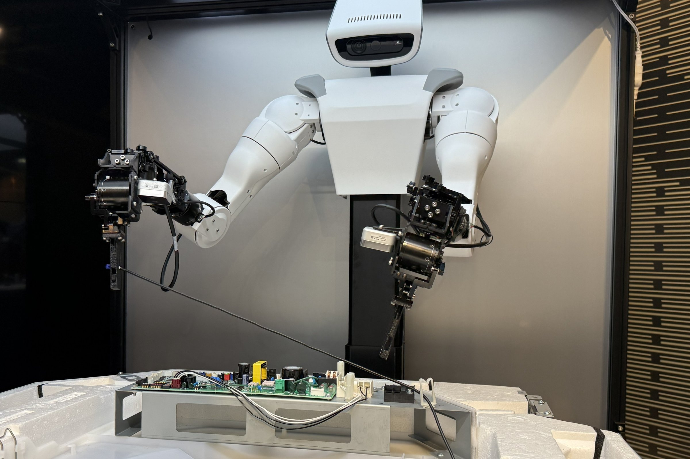 日立製作所が製作した人型ロボットは、10秒程度で柔らかいケーブルを電子基板上の固定具3カ所に通す様子を見せた（写真：日経クロステック）