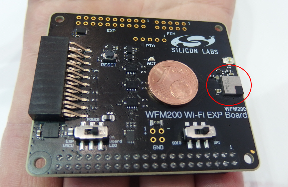 評価ボード上のWiFiトランシーバーモジュールの「WFM200」（赤丸で囲んでいるパッケージ）。その左は1ユーロ・セント・コイン。日経 xTECHが撮影。