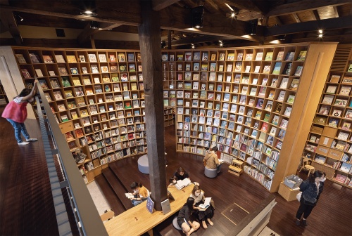 閲覧室Cをギャラリー(空中廊下)から見下ろす。大黒柱を中心に円弧状の大きな書棚が取り巻く。子どもの手の届かない高さに飾られた本は、必ず低い位置に同じ本がある(写真:吉田 誠)