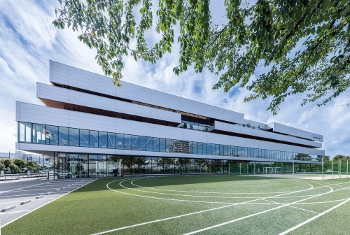 運動スペースから見た建物の北側ファサード。コニカミノルタのシンボルロゴを思わせる5本のラインが特徴だ。運動スペースは、昼休みや休日に社員がサッカーやテニスなどで利用している(写真:母倉 知樹)