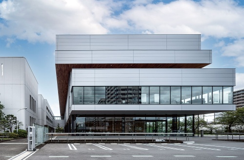 北東から見た外観。南側の既存棟を遮るように建物を建てた。断面は周辺環境に応じて各階のボリュームをずらした構成にし、内部空間に変化をつけた(写真:母倉 知樹)