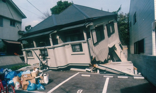 阪神大震災で、ねじれて倒壊した住宅。前面に壁がないことから、前面が左に大きく変形して倒壊している。後ろ側は、まだ2階を支えているところもある（資料：筆者）