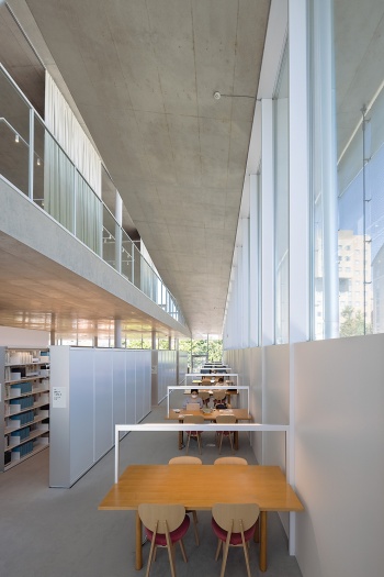 3階東側の閲覧席。木製椅子は旧図書館で使っていたものを再利用。木製テーブルも再利用し、足りない分は同じ木で製作。照明は書架やテーブルに取り付け、天井への設置を抑えた(写真:吉田 誠)