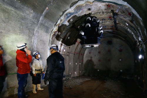 写真1■ 大石西山排水トンネルの切り羽付近。トンネルの天端からぶら下がるように見える「リーミングビット」を回転させて、鉛直上向きにたて坑を掘削する（写真：安川千秋）
