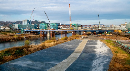 写真1■ 架設中の足羽川橋梁を上流から見る。青い桁がスーパー桟橋。桟橋による水位上昇を抑えるため、手前の高水敷を切り下げた。2019年12月撮影（写真：大村 拓也）