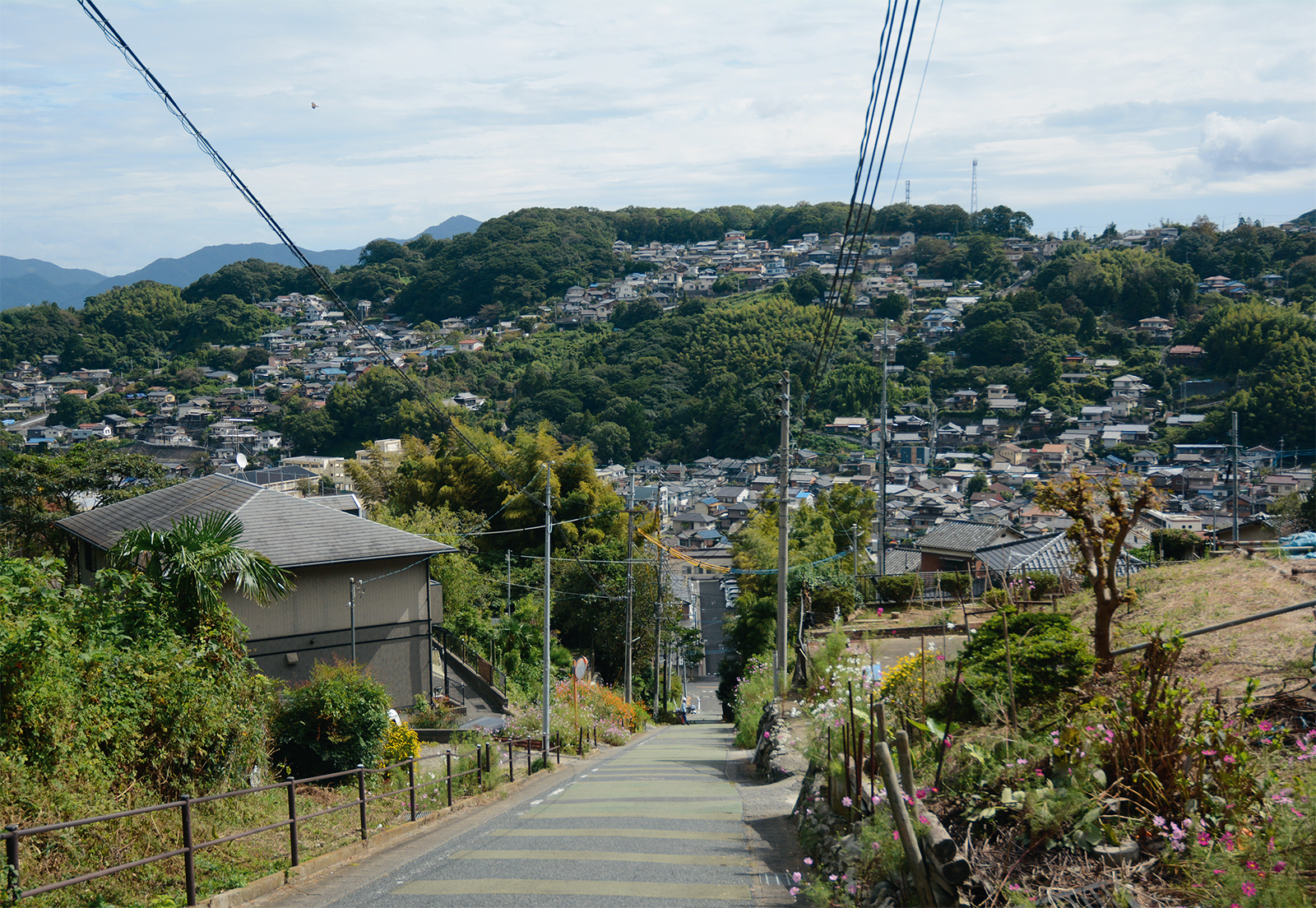 写真1■ 北九州市八幡東区にある20％超の斜度を持つ通称「ゾンコラン坂」の中腹から見た景色。坂周辺や向こう側に見える宅地などは、市街化調整区域への編入候補地だ（写真：日経コンストラクション）