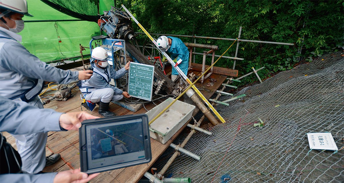 写真1■ 西日本高速道路会社が発注した松山自動車道法面補強工事で奥村組土木興業が遠隔臨場に対応している様子。この現場では新型コロナウイルスの感染拡大よりも前から奥村組土木興業の提案で試行を始めていた。2020年6月に撮影（写真：日経コンストラクション）