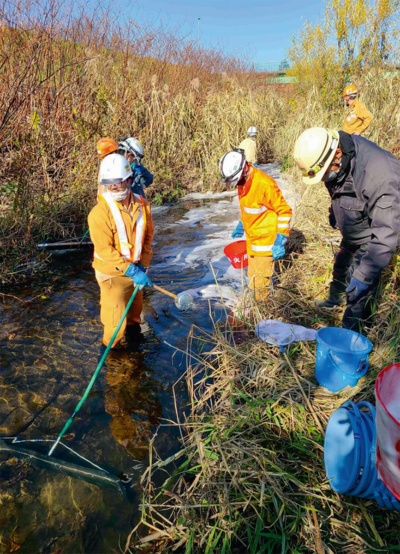 資料3■ 堤防上から川へ流れ落ちた泥土の回収作業の様子(写真:鉄道建設・運輸施設整備支援機構)