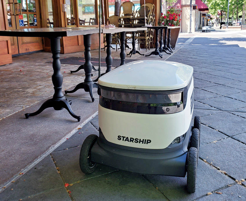 （a）レストランの前に停車中の配送ロボット